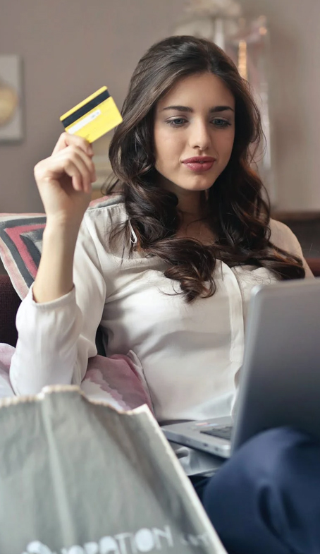 Woman holding credit card while using laptop
